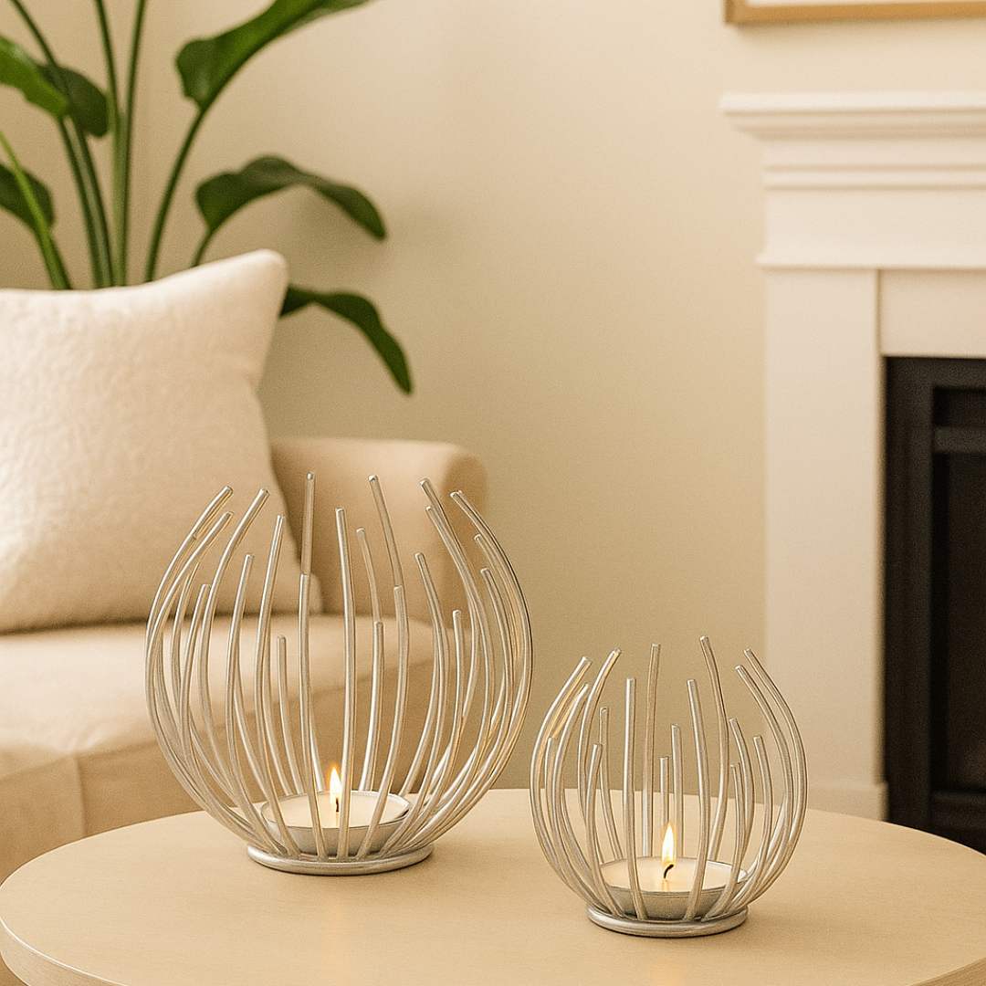 Two decorative Aura candle holders on a table with a plant and sofa in the background from House of Pehr