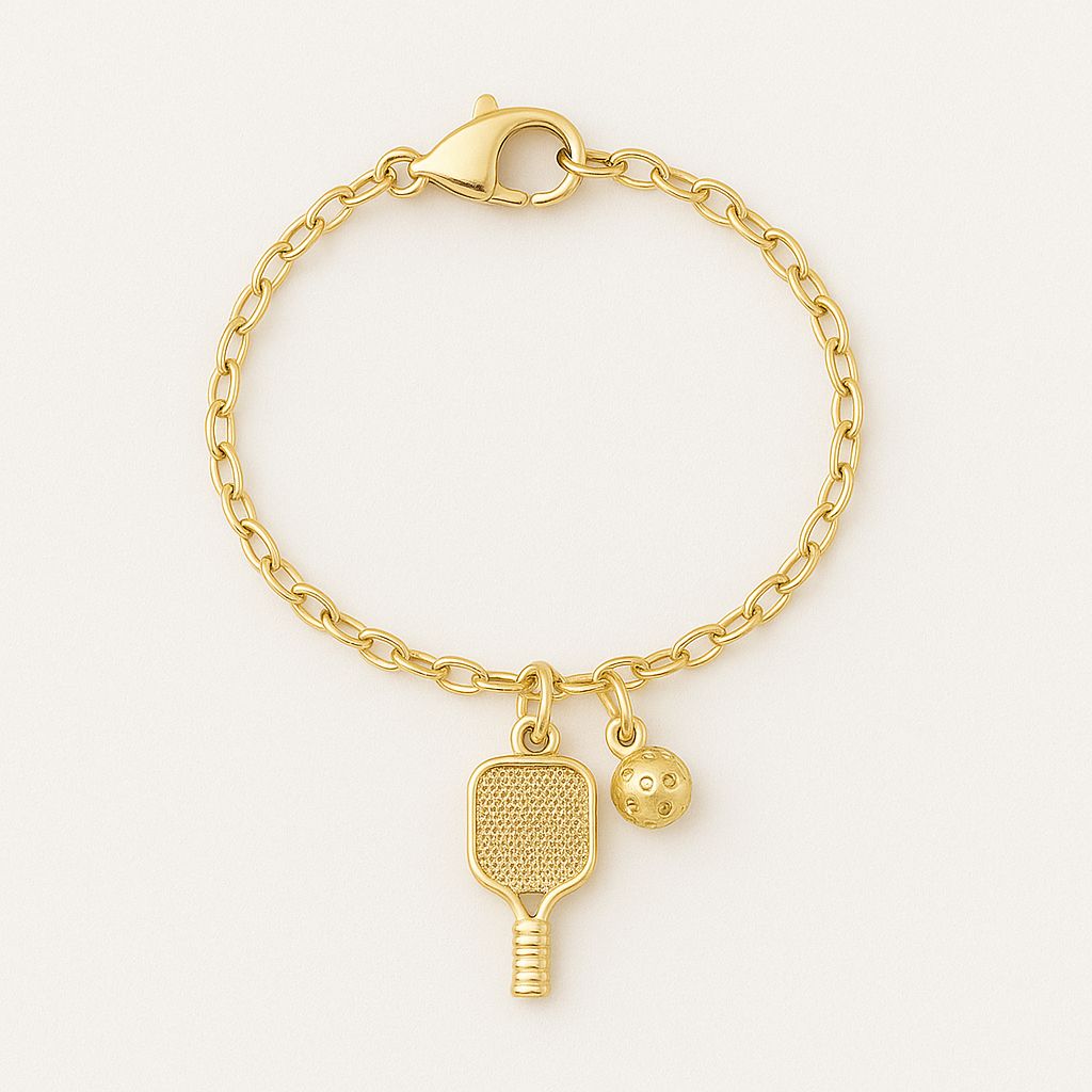 Gold watch charm with pickleball paddle and ball on a Watch against a blurred background