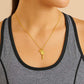 Gold necklace with a tennis racket pendant worn by a person in a gray tank top from House of Pehr