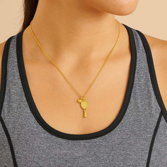 Gold necklace with a tennis racket pendant worn by a person in a gray tank top from House of Pehr