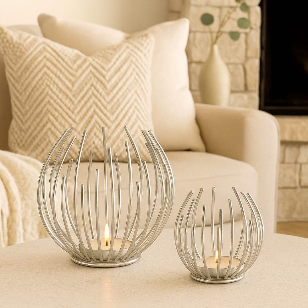 Two decorative Aura candle holders on a table with a plant and sofa in the background from House of Pehr