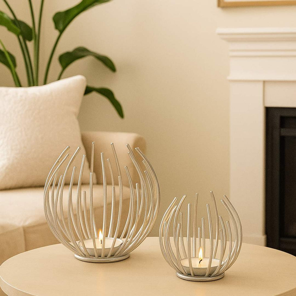 Two decorative Aura candle holders on a table with a plant and sofa in the background from House of Pehr - Image 6