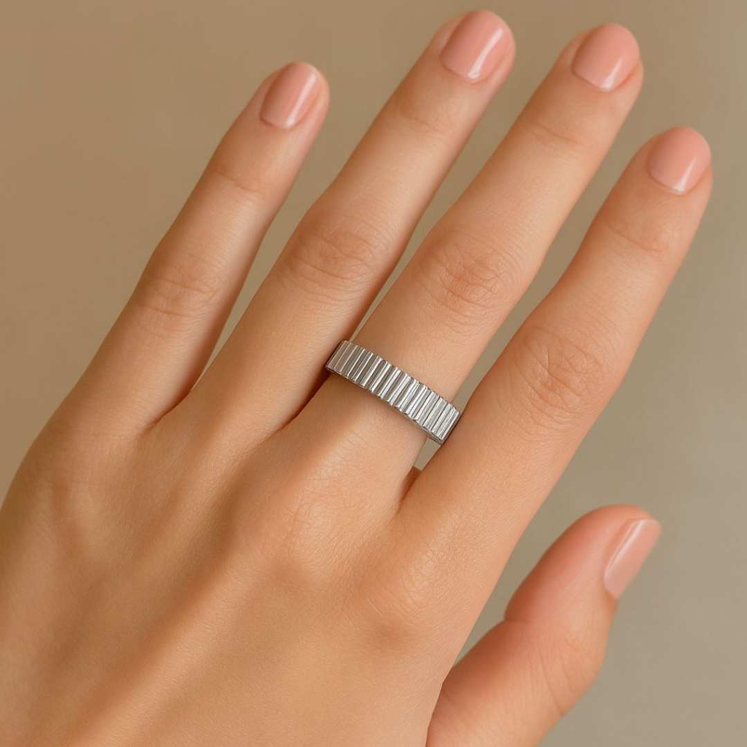 Hand wearing a silver Orbit ring on a beige background