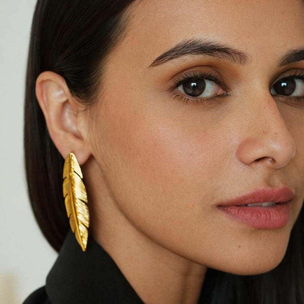 Close-up of a woman wearing gold feather earrings from House of Pehr - Image 3
