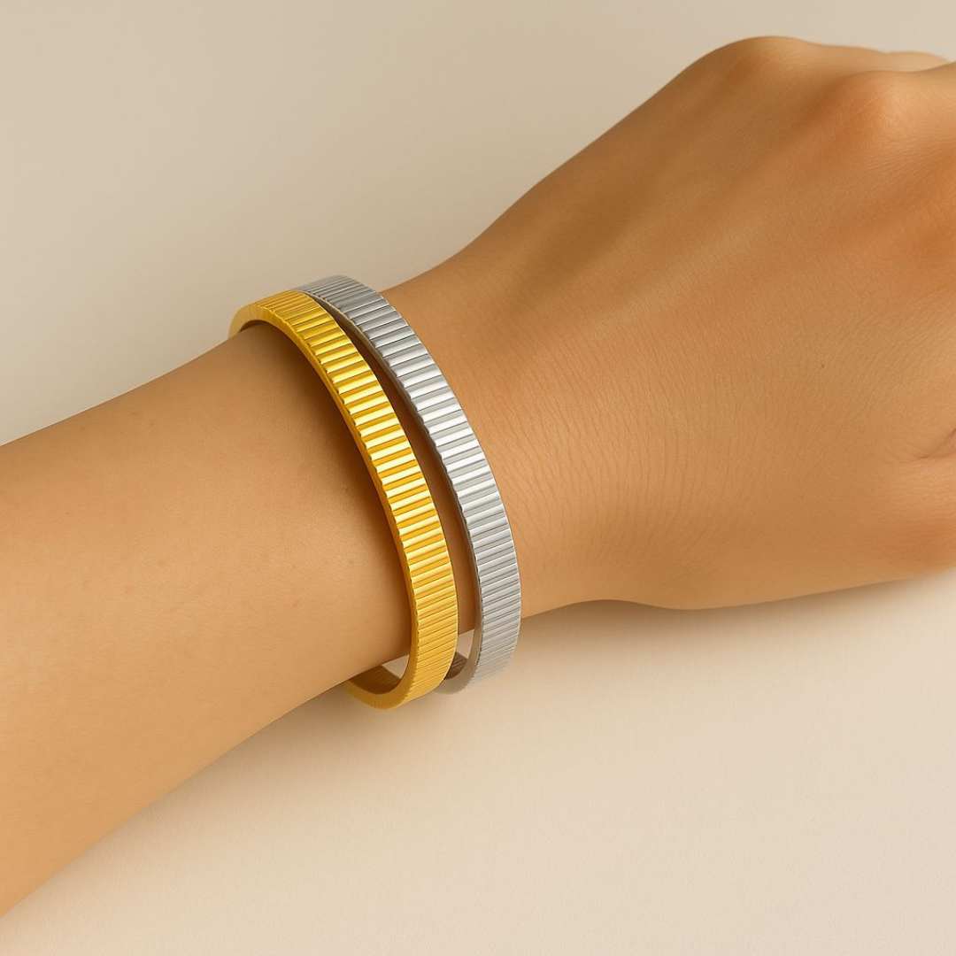 Hand wearing the orbit gold and silver bangle on a beige background from House of Pehr