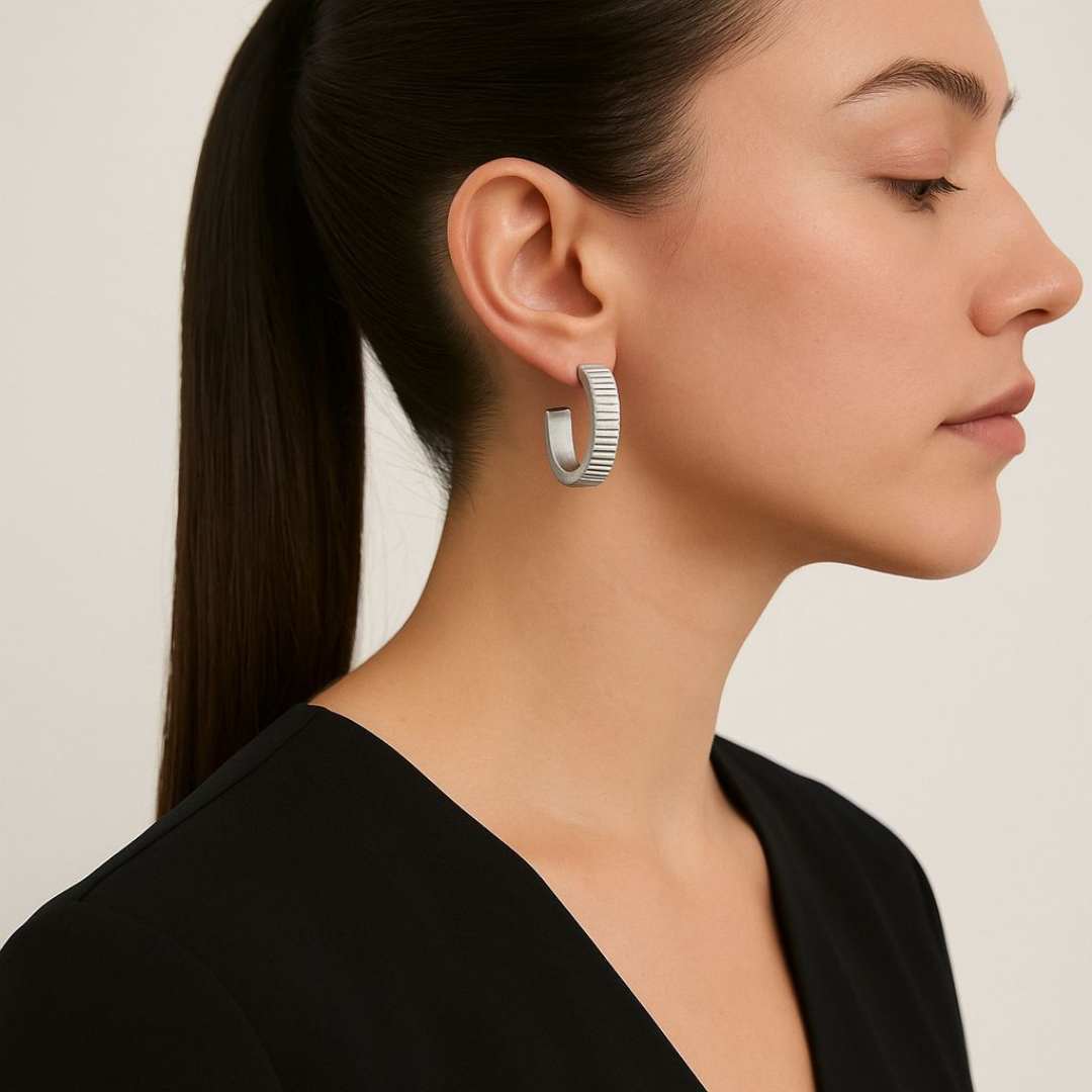 Woman wearing Silver Orbit hoop earrings with a neutral background from House of Pehr