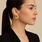 Woman wearing gold Orbit hoop earrings with a neutral background from House of Pehr
