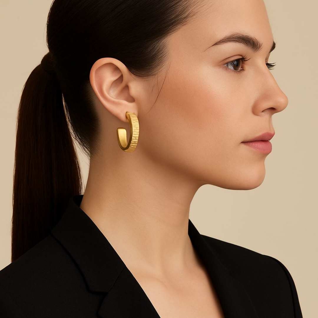 Woman wearing gold Orbit hoop earrings with a neutral background from House of Pehr