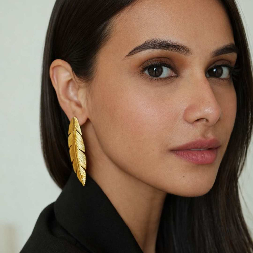 Woman wearing gold feather earrings with a neutral background from House of Pehr - Image 5