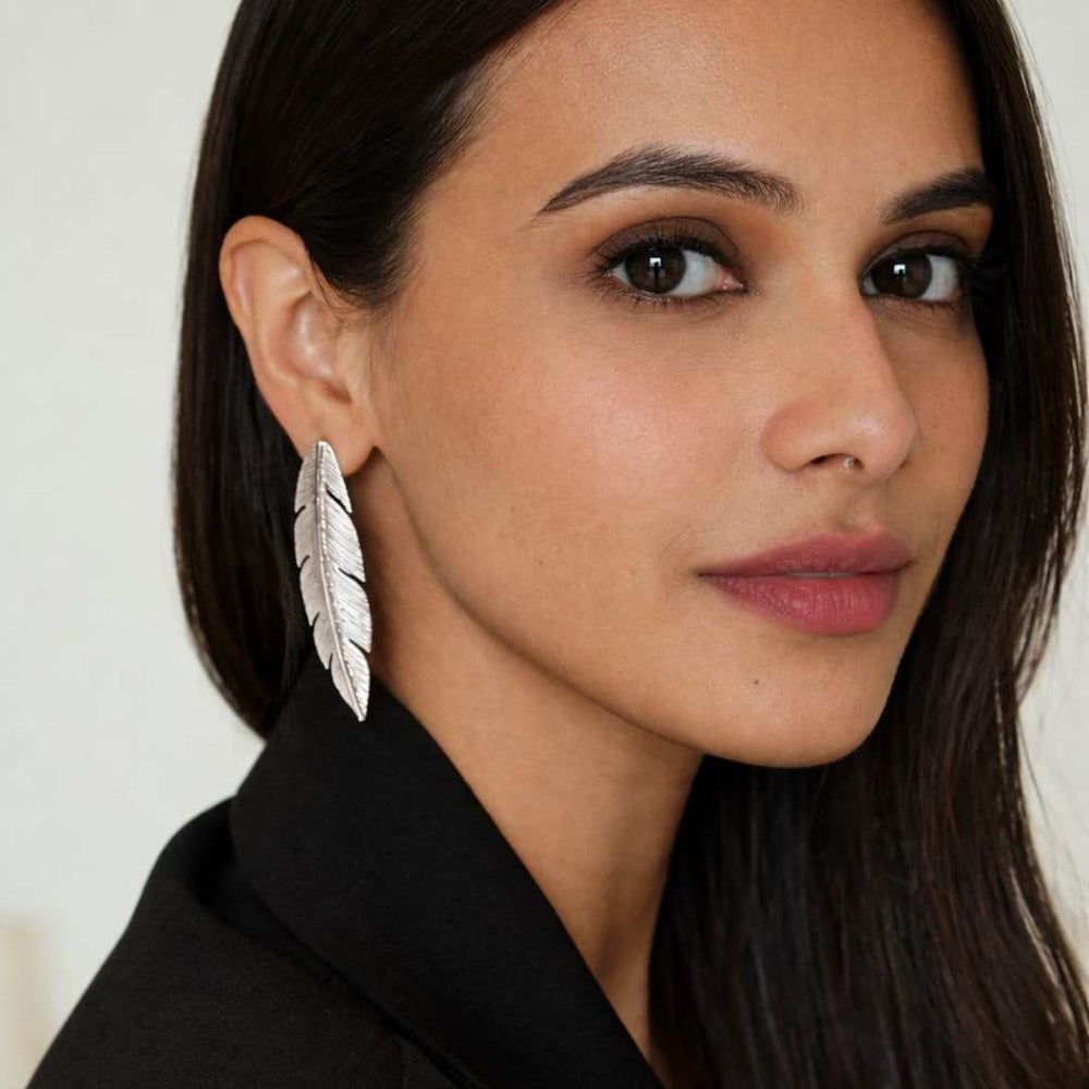 Woman wearing a feather earring with a neutral background from House of Pehr - Image 6