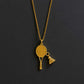 Gold necklace with a badminton racket pendant next to a badminton shuttlecock and racket on a dark surface from House of Pehr