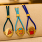 Three colorful rakhi charm bracelets with unique charm designs on a beige surface.