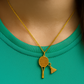 Gold necklace with a badminton racket pendant next to a badminton shuttlecock and racket on a dark surface from House of Pehr
