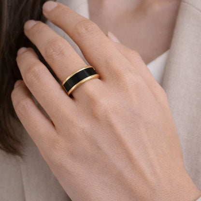 Hand wearing a black and gold ring on a light background - Noire Ring - house of pehr