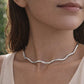 Close-up of a woman wearing a silver necklace with a blurred natural background from House of Pehr