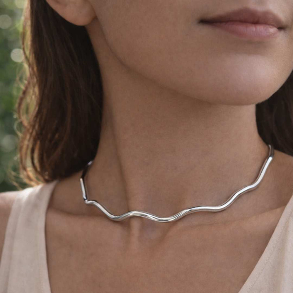 Close-up of a woman wearing a silver necklace with a blurred natural background from House of Pehr - Image 2