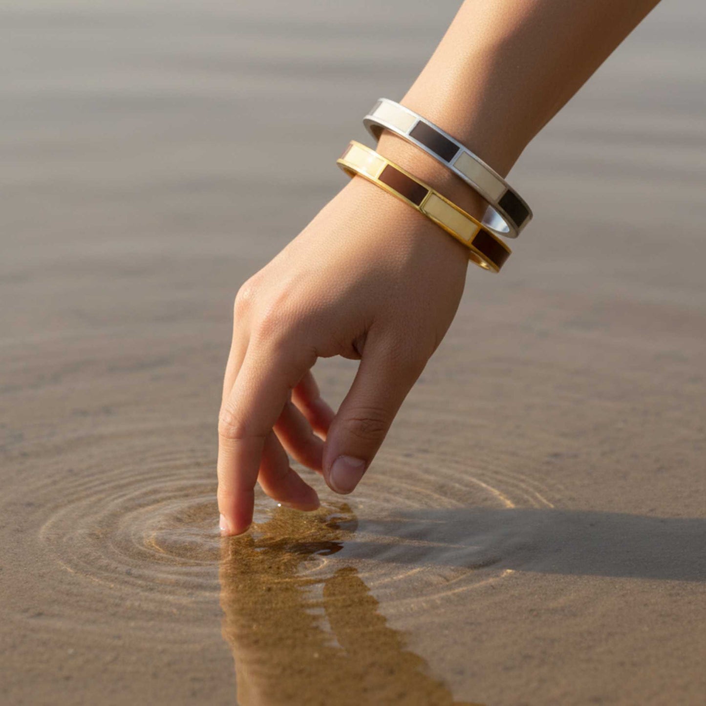 Stacked Dune bangle on a wrist against a beach