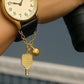 Gold watch charm with pickleball paddle and ball on a Watch against a blurred background