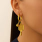 Gold hoop earrings with pickleball paddle and ball charms on a beige background