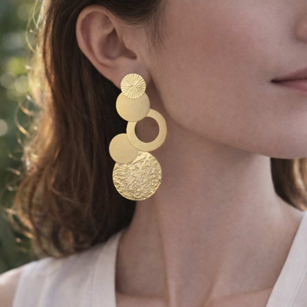 Close-up of a person wearing gold earrings from House of Pehr