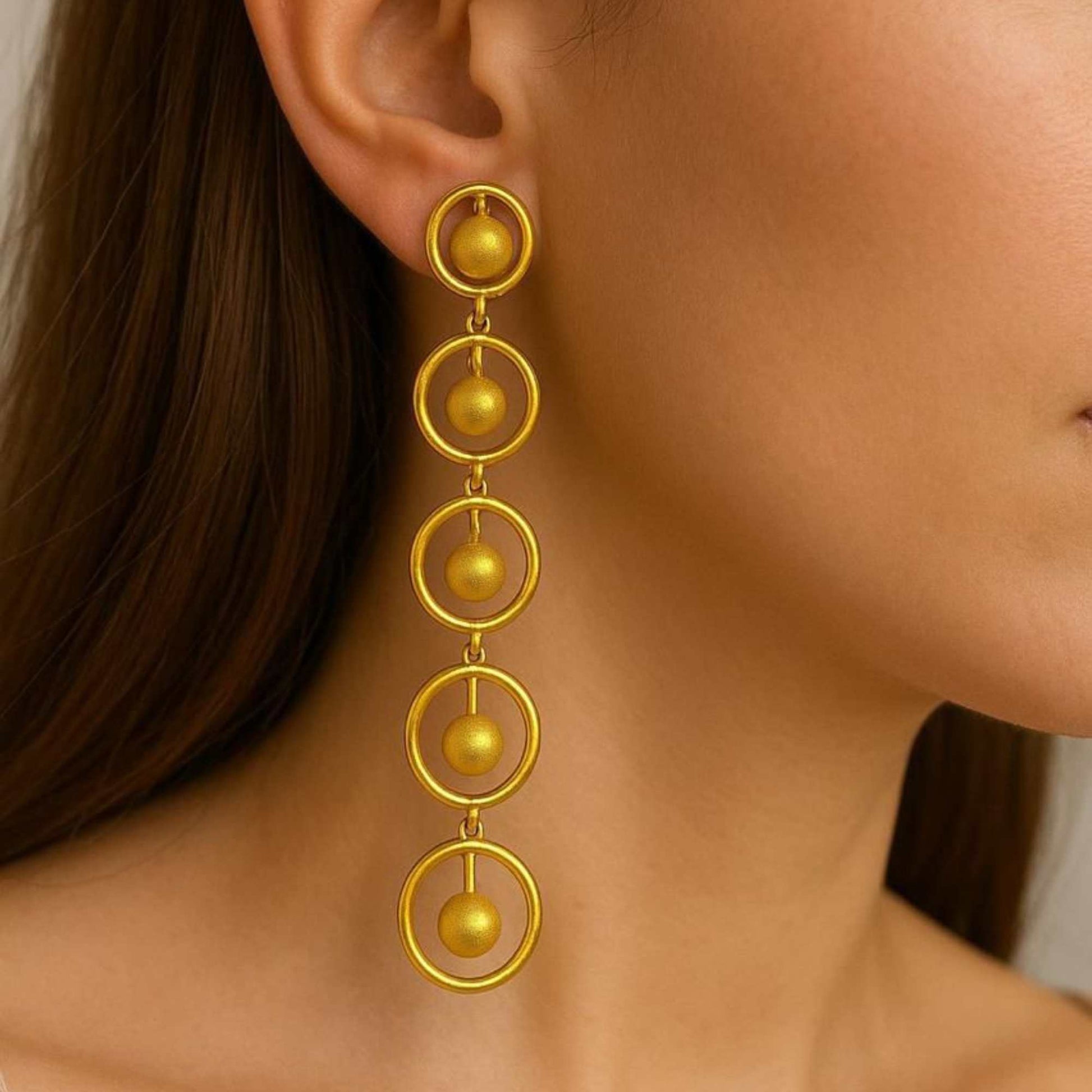 Gold earrings with circular design on a white background, solara earrings from house of pehr