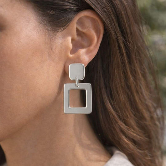 Close-up of a person wearing silver square earrings from House of Pehr