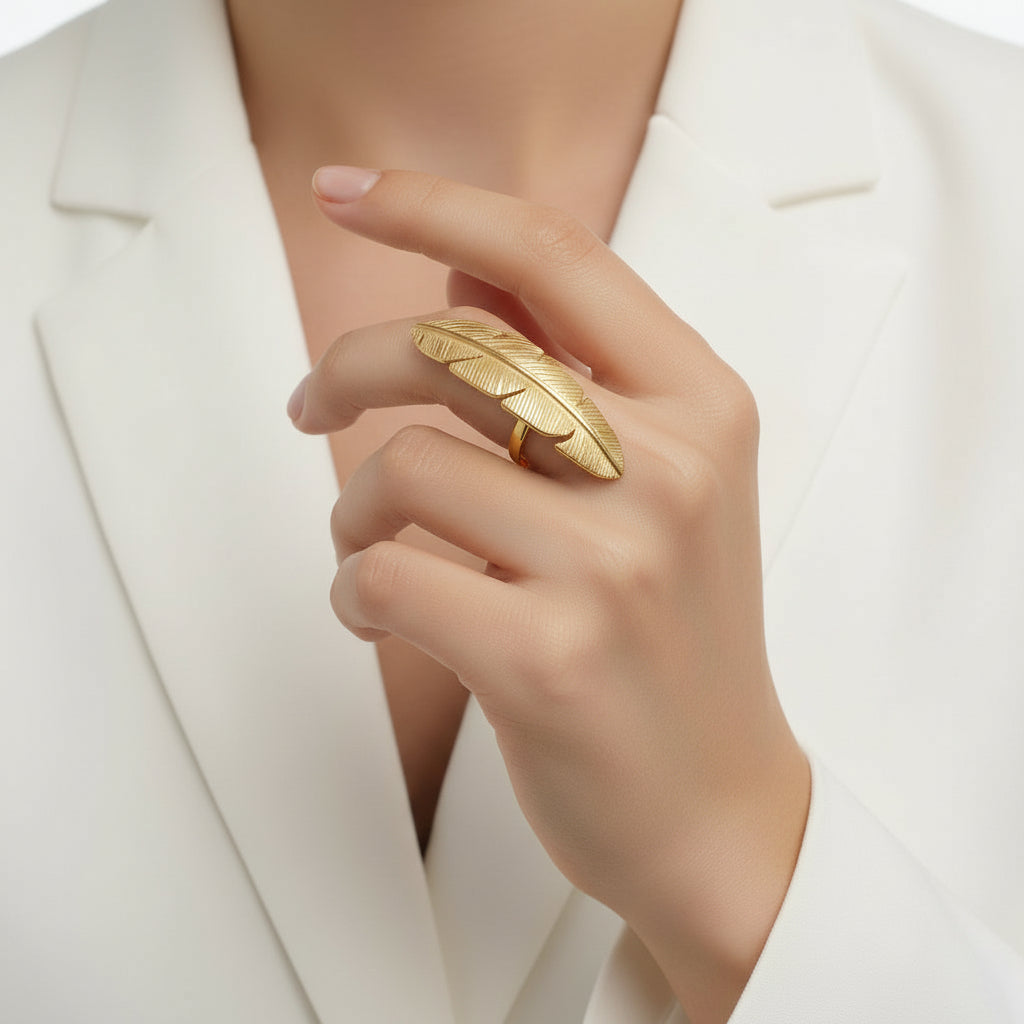 golden feather-shaped ring on a finger, Zephyr Ring from House of Pehr