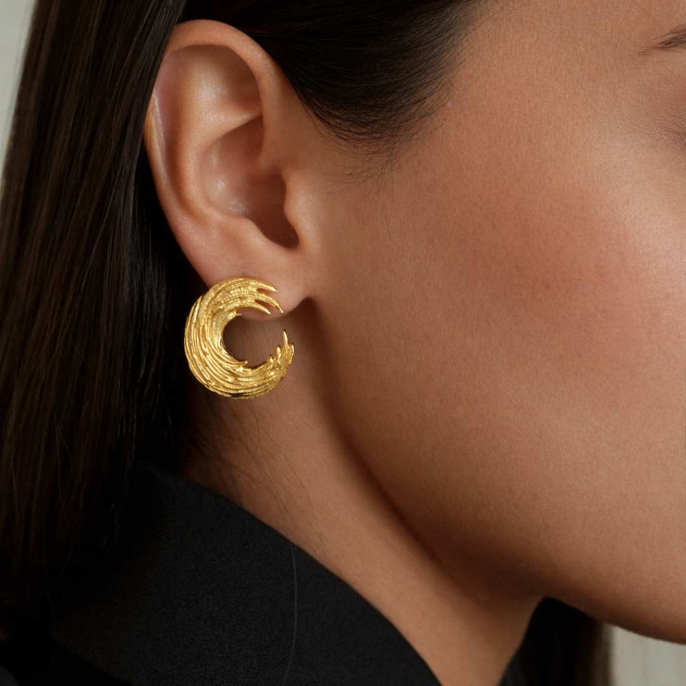 Close-up of a person wearing a gold earring with a textured design from House Of Pehr - Image 5