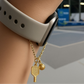 Gold watch charm with pickleball paddle and ball on a Watch against a blurred background