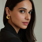 Woman wearing gold earrings with a neutral background from House of Pehr