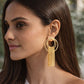 Woman wearing gold hoop earrings with tassels, from House of Pehr