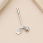A silver-toned metal nail clacker shaped like a golf club, with a small dangling golf ball charm, displayed on a light beige textured background.