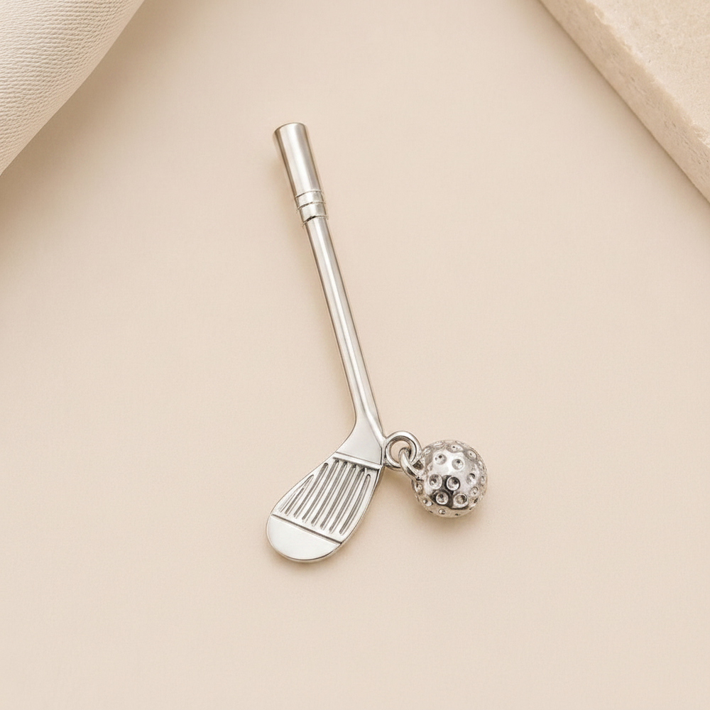 A silver-toned metal nail clacker shaped like a golf club, with a small dangling golf ball charm, displayed on a light beige textured background. - Image 9