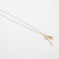 Gold necklace with a badminton racquet with shuttlecock pendant on a light gray background from House of Pehr