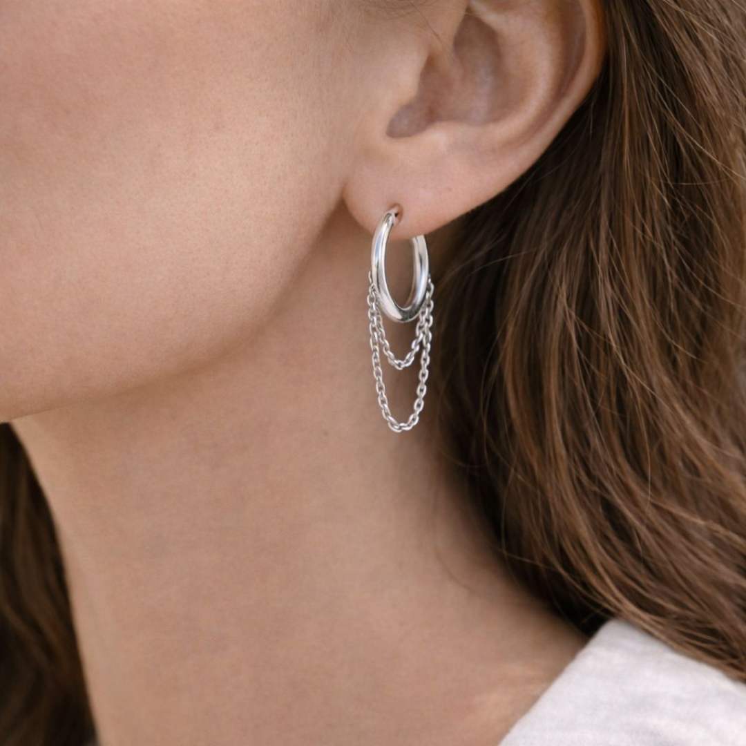 Close-up of a person wearing a silver hoop earring with a chain detail House of Pehr 