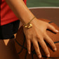 Hand wearing a gold bracelet with ball and shoes charms for basketball